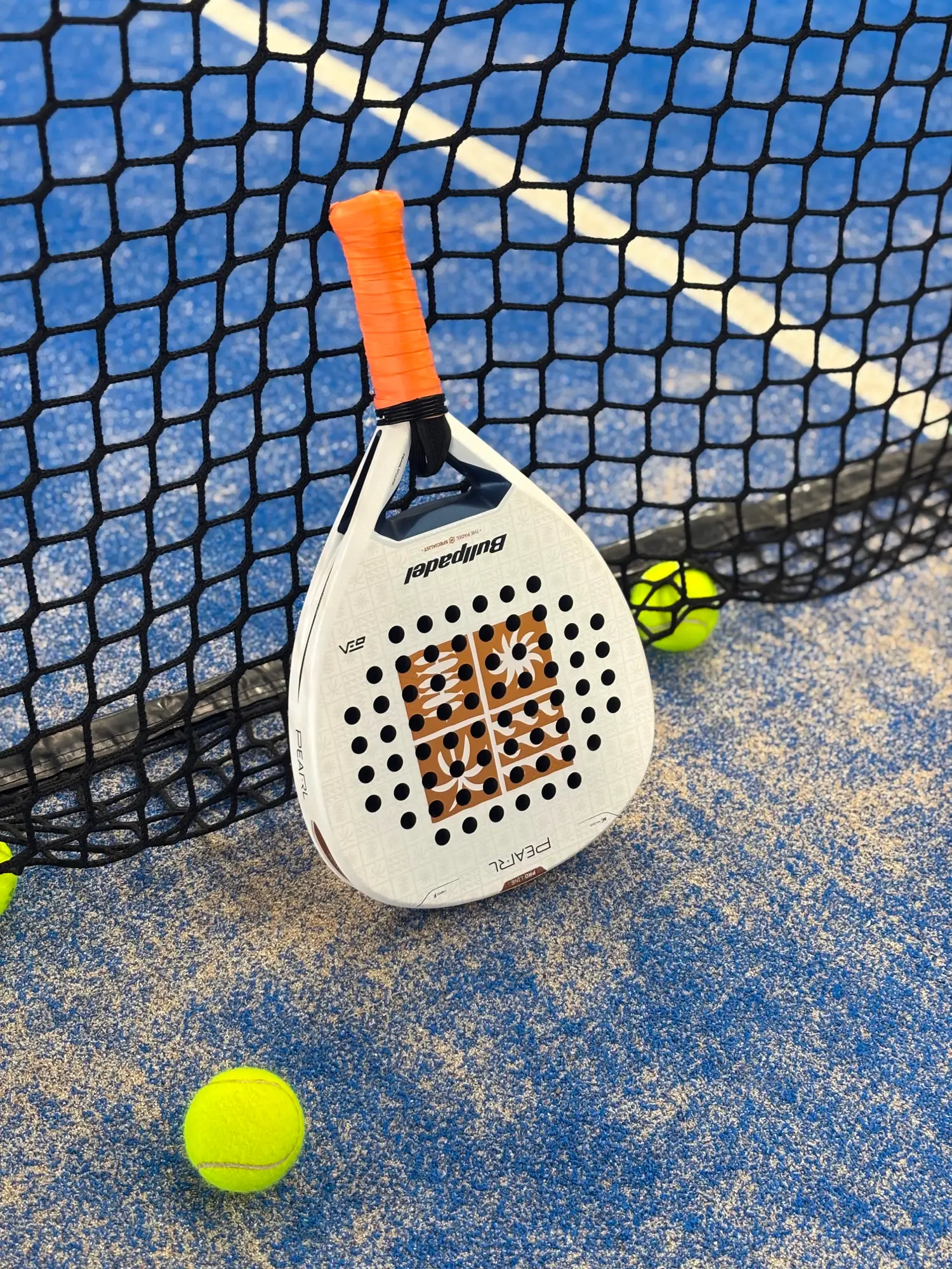 Padel racket and ball resting against the court net