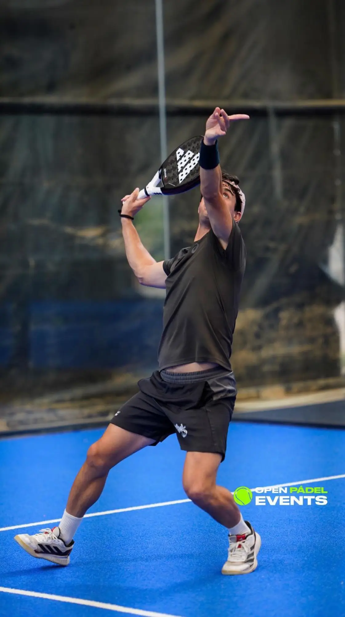 Padel player hitting an overhead smash on an indoor court in Valencia